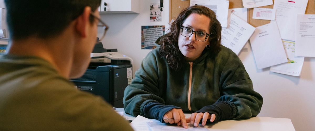 2 Personen sitzen einander an einem Schreibtisch gegenüber, es ist eine typische Rechtsberatungssituation.